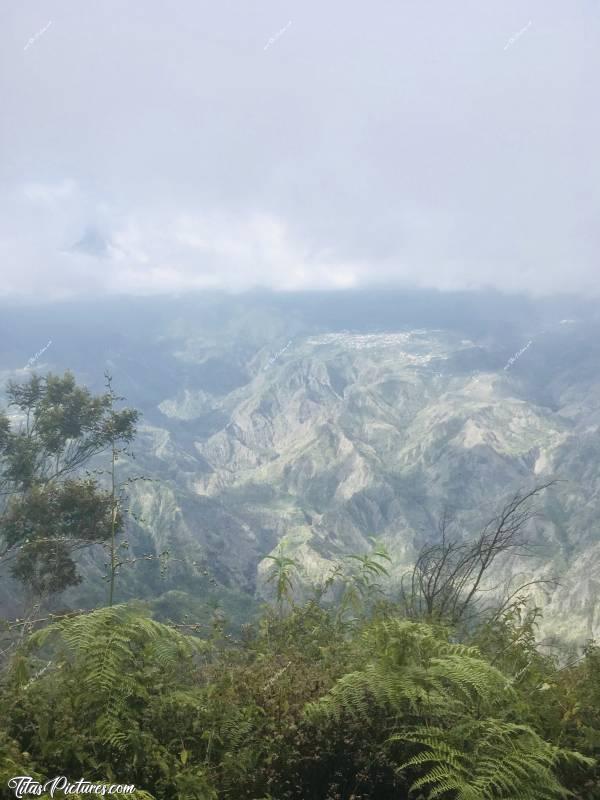 Photo Le Cirque de Cilaos : Pas facile de pouvoir admirer cette vue bien dégagée. Pour cela, il faut se lever très tôt😅 Car dès la fin de matinée, ça se couvre de nuages 😔
Les petits points blancs regroupés dans le fond sur la montagne sont des habitations pour info.c, Cirque de Cilaos