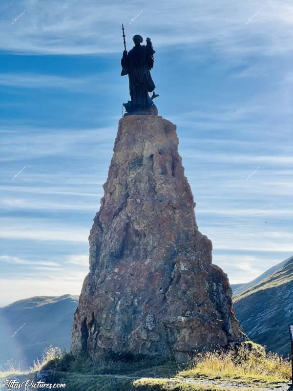 Photo Statue de Saint Bernard de Menthon : Cette statue se trouve tout près de la frontière italienne, au Col du petit Saint Bernard. 
Saint Bernard, dit de Menthon, d'Aoste, des Alpes ou encore du Mont-Joux, naît vers 1020. Archidiacre d'Aoste, il fonde vers 1050 un hospice, au col du Mont-Joux, qui porte désormais son nom : l'hospice du Grand-Saint-Bernard.
Il reconstruit un hospice à Colonne-Joux, celui du Petit-Saint-Bernard. Prédicateur itinérant à succès, il meurt à Novare le 12 juin 1081 ou 1086 et y est enseveli le 15, jour retenu pour sa fête.
Il est canonisé par l'évêque de Novare, en 1123, inscrit au calendrier romain par le bienheureux Innocent XI, en 1681, puis déclaré patron des alpinistes, des voyageurs et habitants des Alpes par Pie XI, en 1923.
Une légende du XVe siècle le fait naître en 923 dans la famille de Menthon, et mourir en 1008. Source de confusions, cette légende inspire encore de nos jours ses biographies et son iconographie dominante.c, Statue de Saint Bernard de Menthon