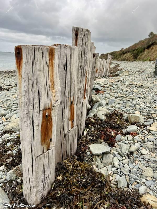 Photo Plouezoc’h : Petite randonnée pluvieuse à Plouezoc’h, dans la Baie de Morlaix. Ces vieux poteaux de chemin de fer ont été dressés à cet endroit, pour protéger des vagues, l’escalier qui se trouve sur la droite.c, Plouezoc’h, plage, galets